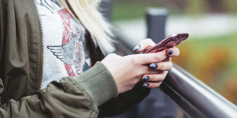 woman outdoors holding smartphone and scrolling through pages