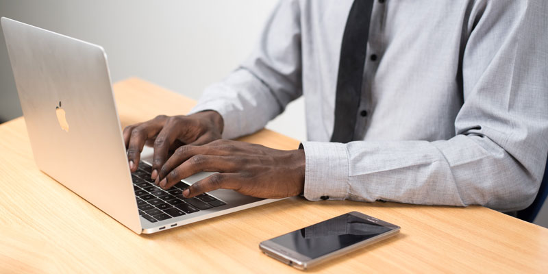 man using laptop with smartphone nearby