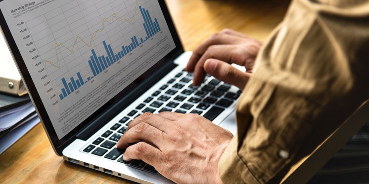 typing on laptop with metrics and graphs on screen